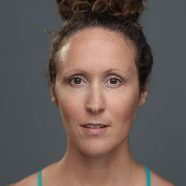 Maegan with her hair pulled into a bun, dressed in a light-green tank top